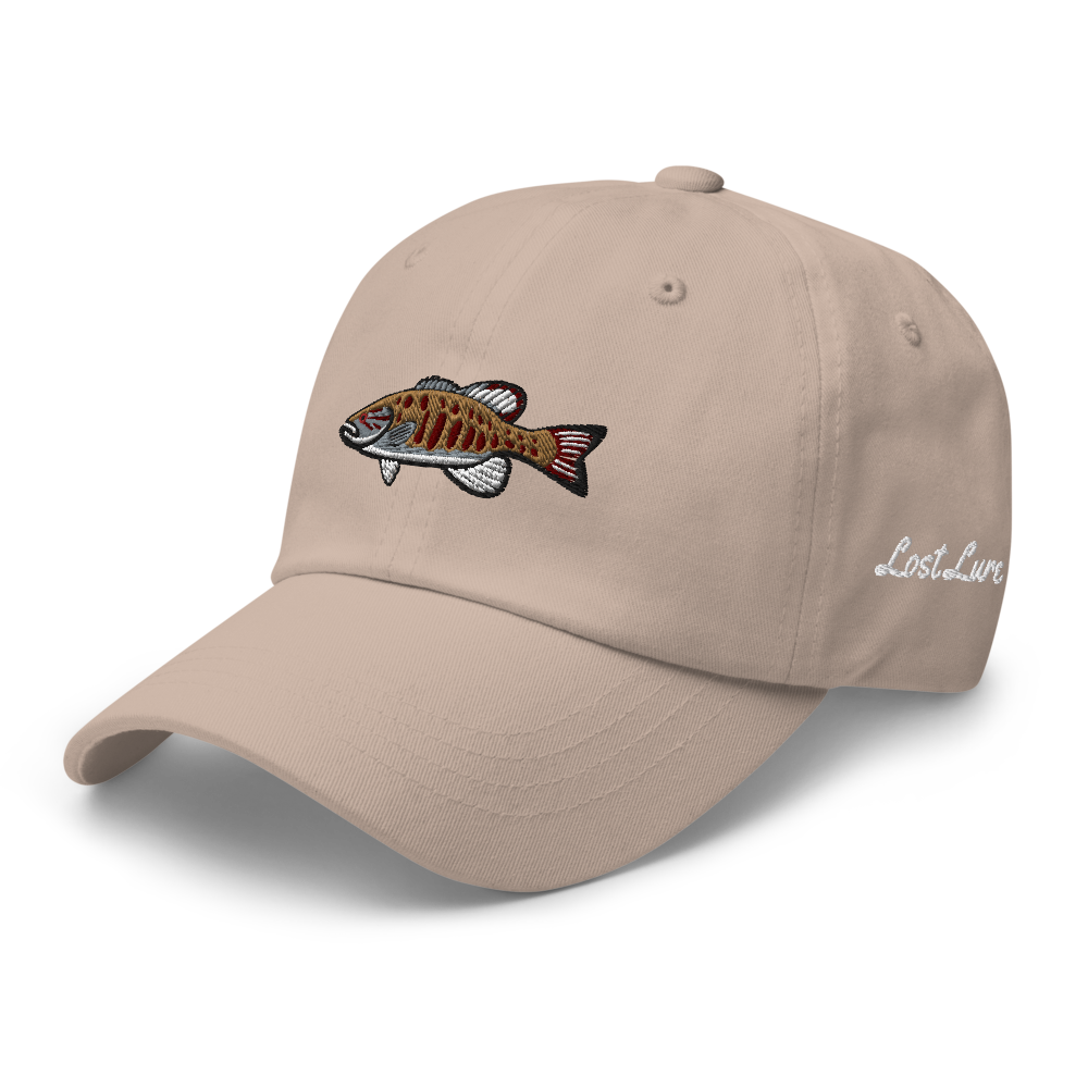 A smallmouth bass fishing hat / dad hat with a simple embroidery design of a smallie. Tan hat, front left side.