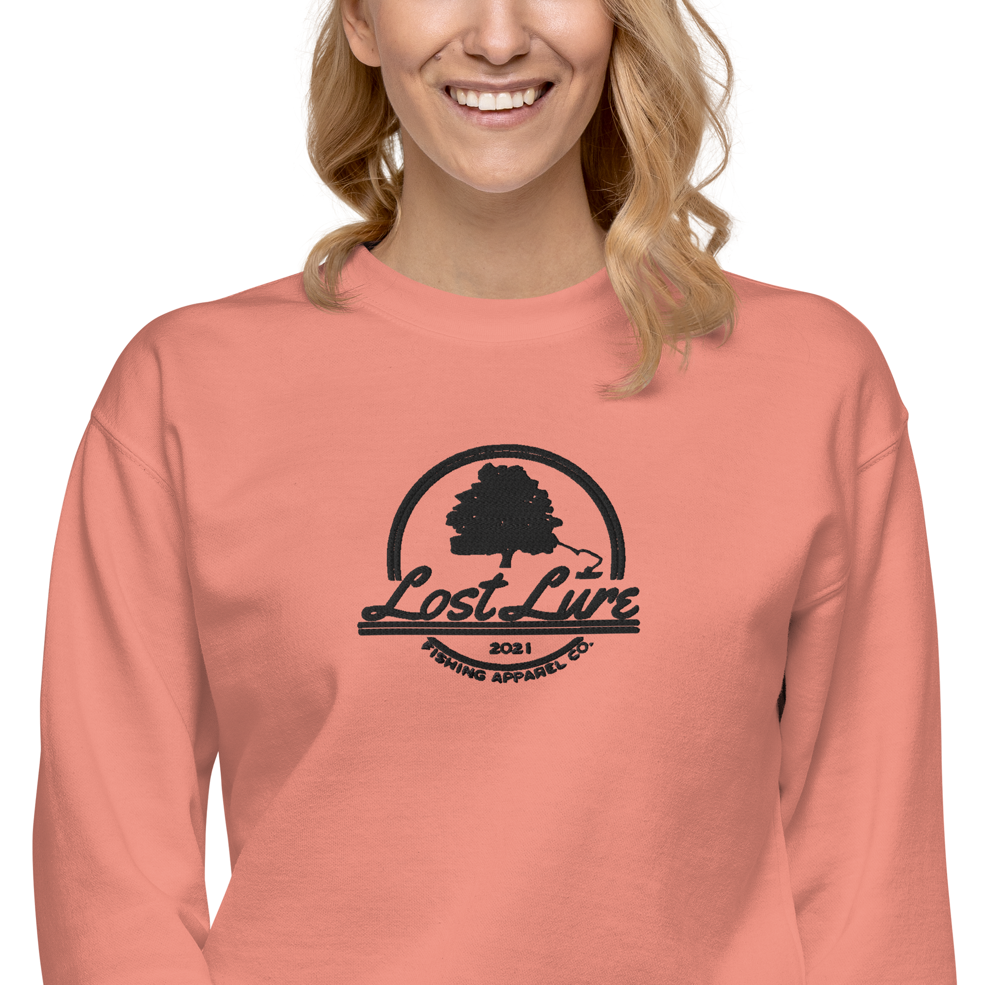 Woman wearing pink fishing sweatshirt with embroidered Lost Lure logo.